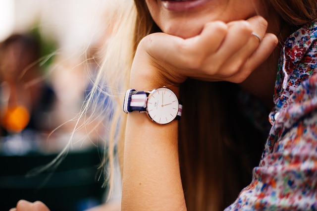 This is an image of a female with her let down, her palm on her chin and her hand wearing a wristwatch